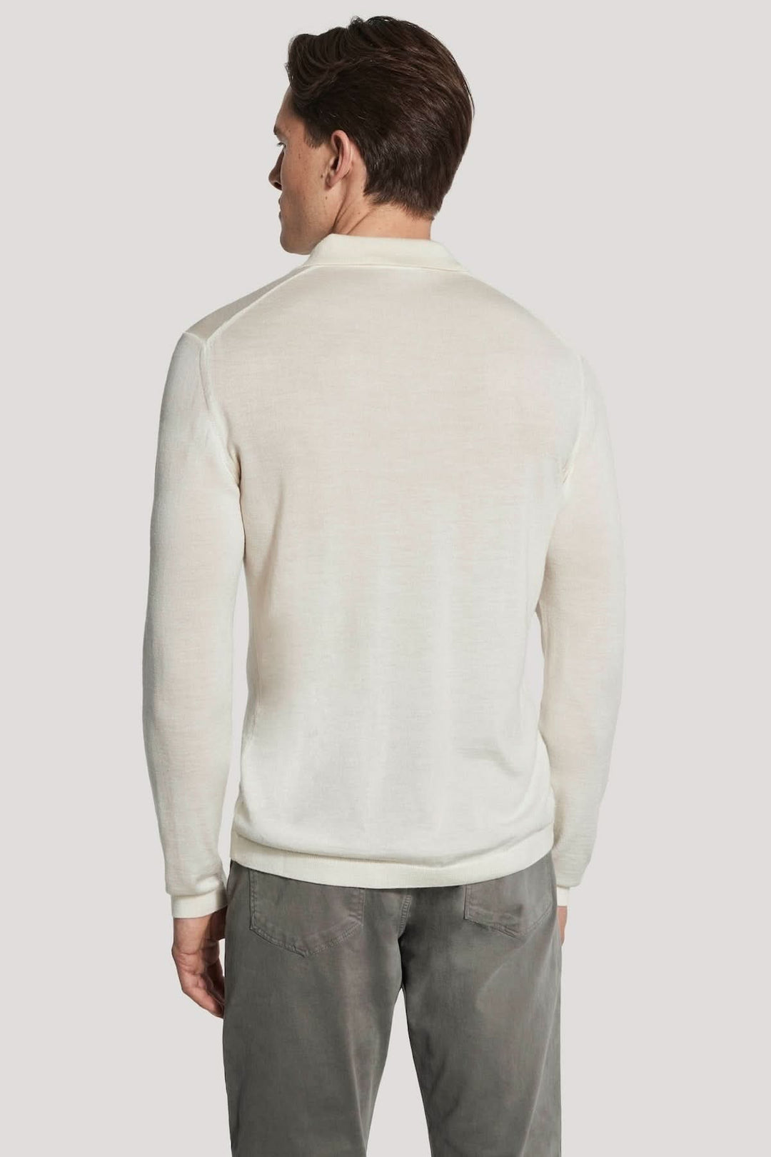 Homme portant un Polo manches longues en laine mérinos et soie blanc, vu de dos, élégant et moderne, idéal pour le confort quotidien.