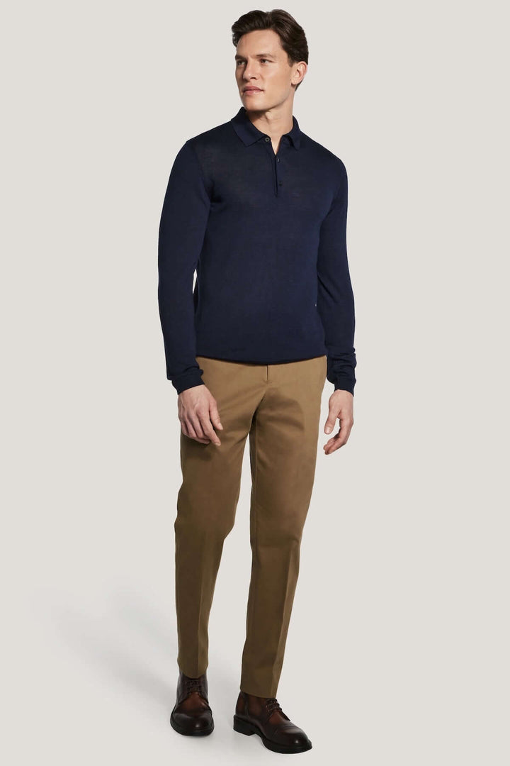 Homme portant un polo manches longues en laine mérinos et soie avec des épaules montées, couleur bleu marine, style moderne et élégant.
