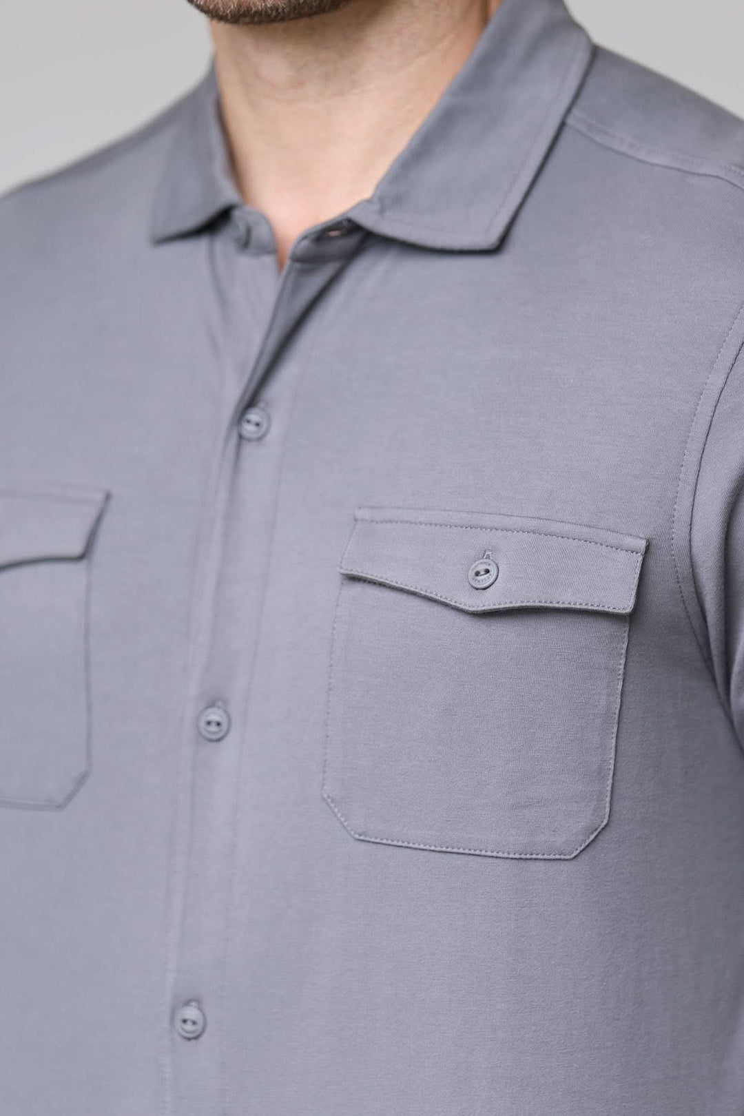 Homme portant un polo à poches boutonnées avec manches longues et col chemise, élégant et décontracté, tissu doux.