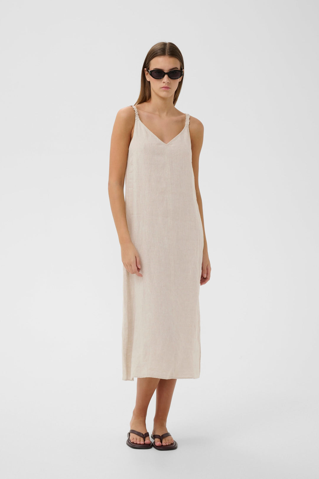 Robe Elinor midi fluide à bretelles fines, élégante avec encolure en V, 100% lin, coupe ample pour un confort optimal et mouvement élégant.