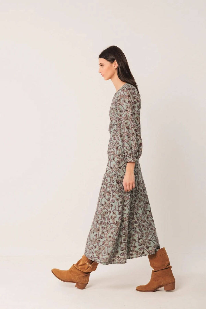 Robe longue au motif géométrique avec manches bouffantes et bottes en daim pour un style bohème chic.