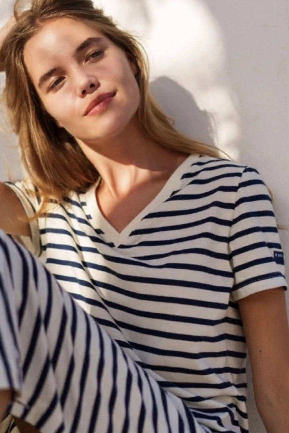 Femme portant une robe longue rayée Eze avec encolure en V, style chic et décontracté pour l'été, détails de boutons décoratifs.