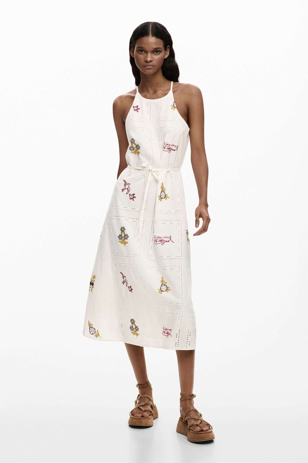Femme portant une robe midi à broderies délicates, coupe fluide, taille ceinturée, idéal pour l&
