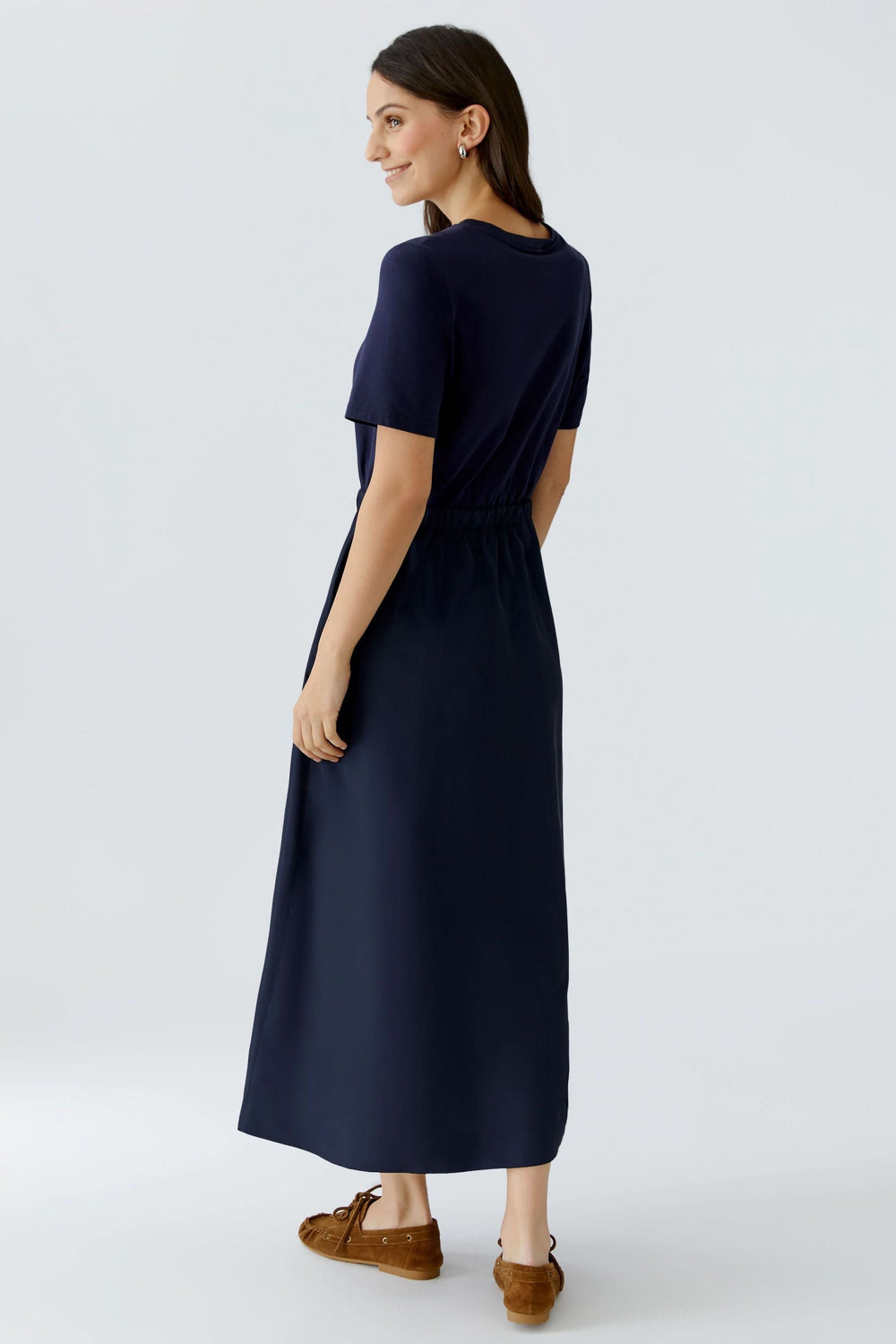Femme portant une robe midi à taille ajustable, vue de dos, mettant en valeur l'ajustement élégant et le style contemporain minimaliste.