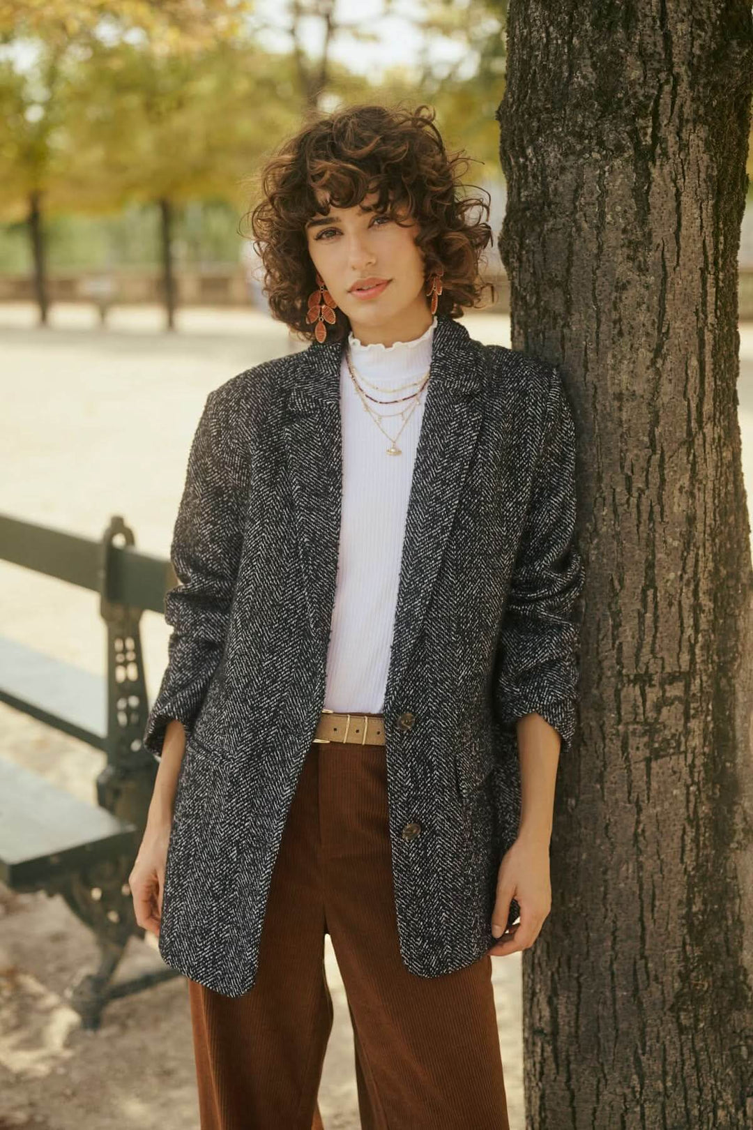 Femme en veste grise devant un arbre dans un parc