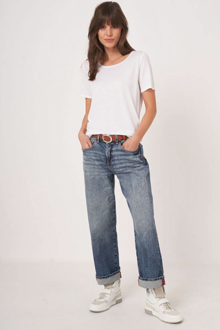 Femme portant un T-shirt col rond manches courtes blanc avec un jean décontracté, style minimaliste et confortable.