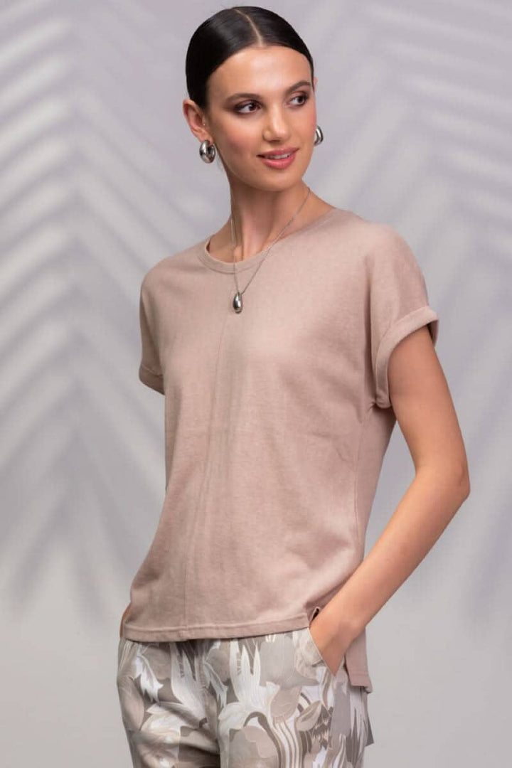 T-shirt beige à encolure ronde porté avec un pantalon à motifs, look décontracté et moderne.