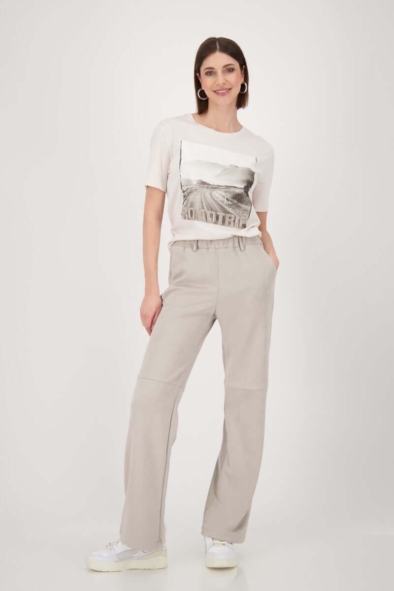 Femme portant un T-shirt imprimé "road trip" manches courtes avec un look casual chic, parfait pour un style décontracté.