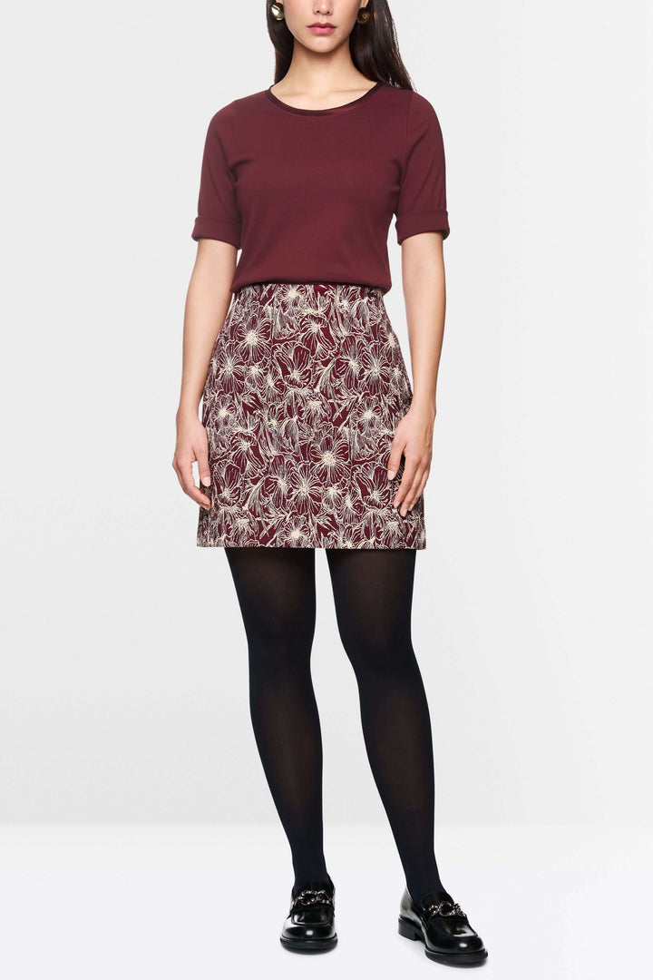 Modele portant un T-shirt manches courtes bordeaux avec une jupe à motifs, idéal pour un look décontracté ou élégant.
