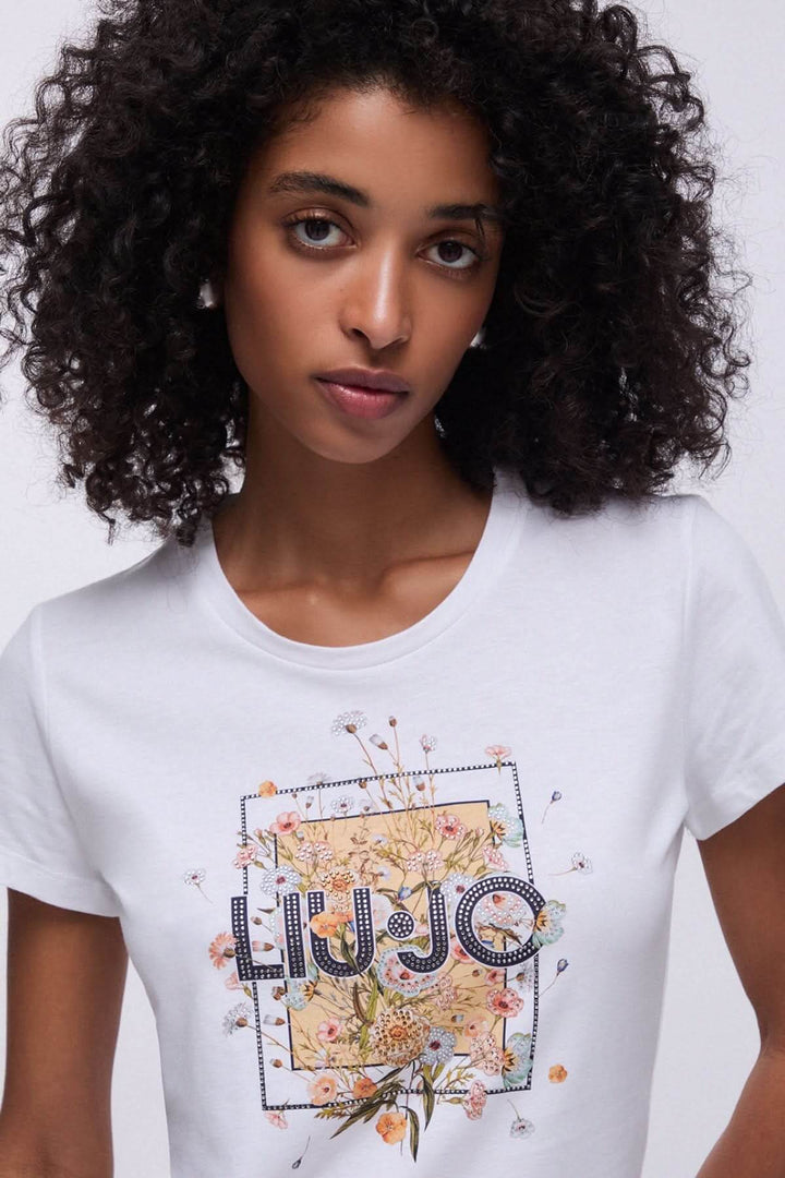 Femme portant un t-shirt à manches courtes avec imprimé graphique floral élégant, idéal pour une tenue décontractée et stylée.