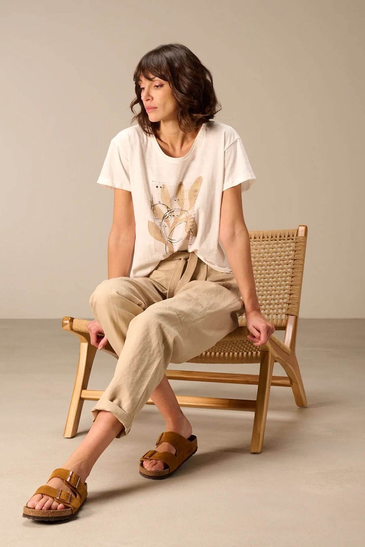 Femme portant un T-shirt à manches courtes coupe décontractée assise sur une chaise, style casual élégant.