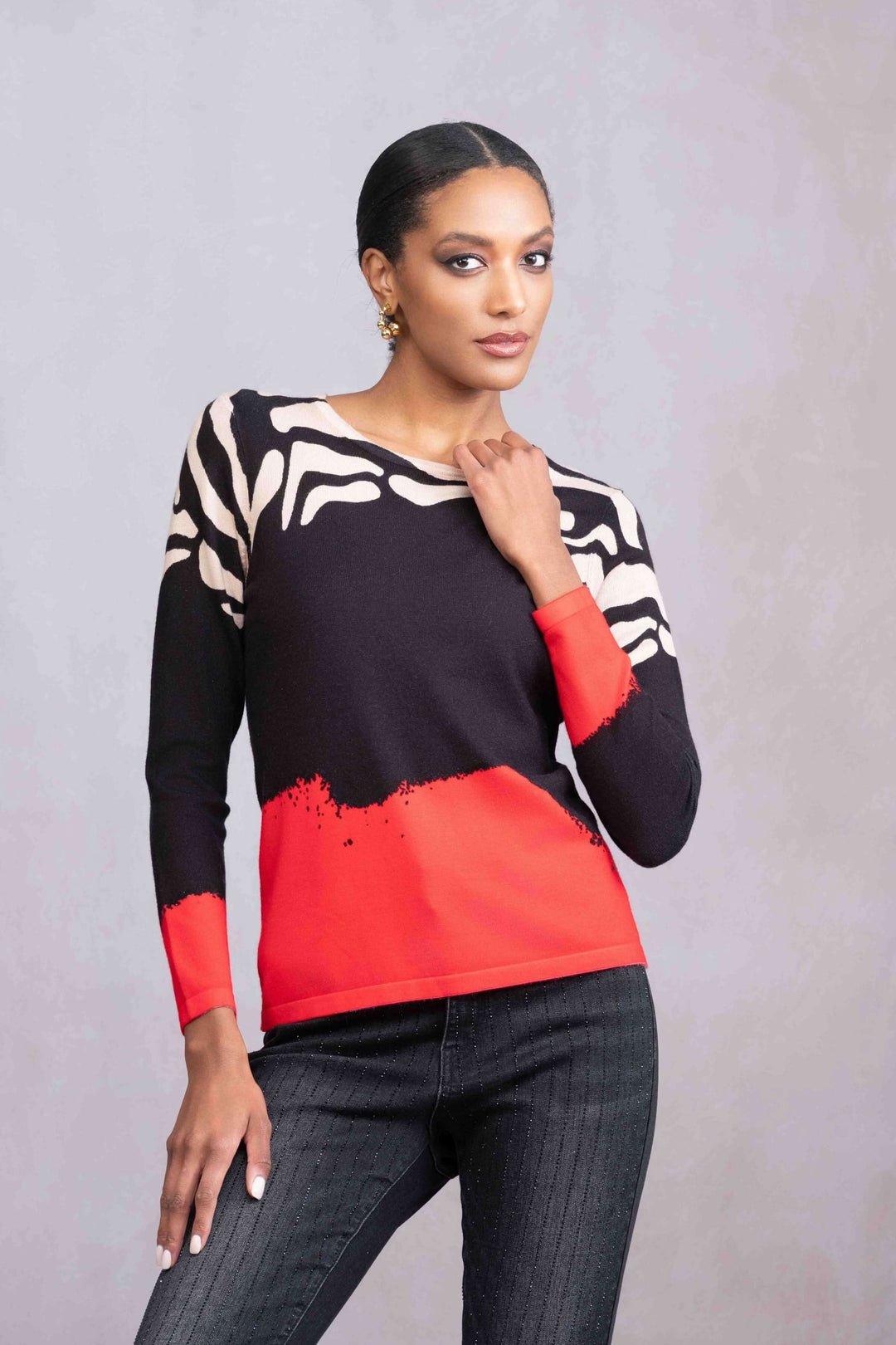 Femme portant un tricot imprimé tricolore avec motif animalier et manches longues, style graphique audacieux.