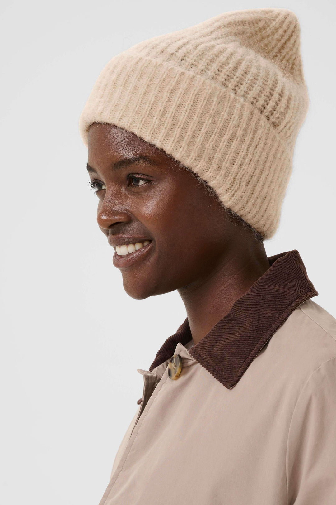 Femme portant la Tuque Sanja en tricot côtelé beige, style moderne et décontracté.