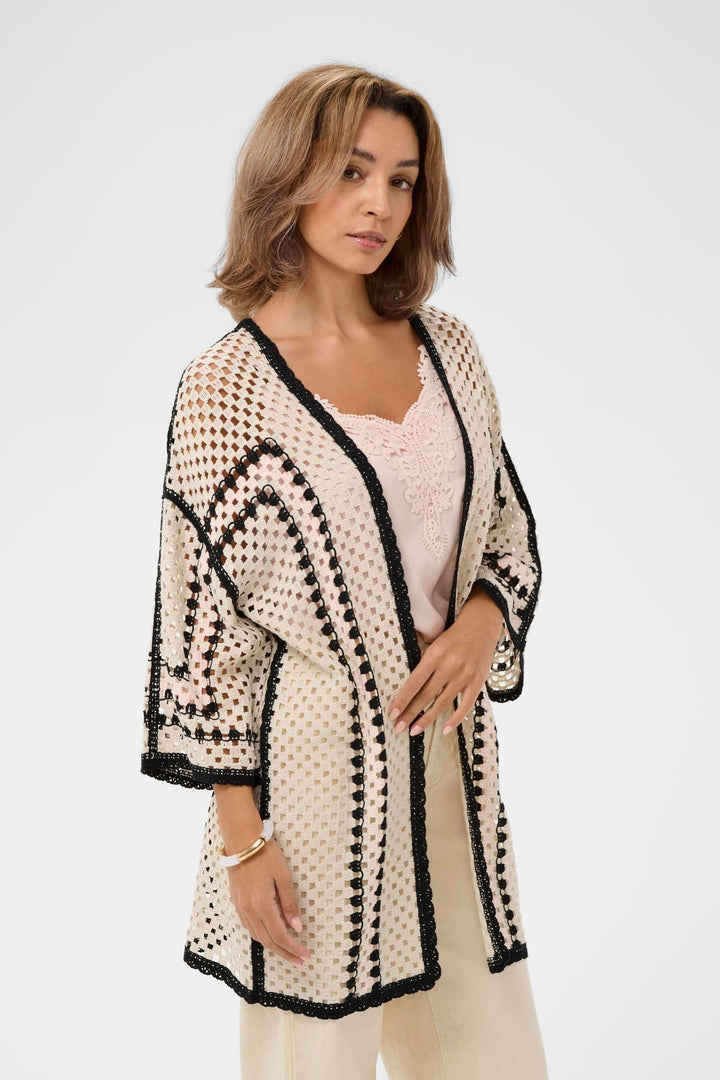 Femme portant une Veste Free ouverte en crochet avec bordures contrastantes et manches larges trois-quarts, style bohème élégant.