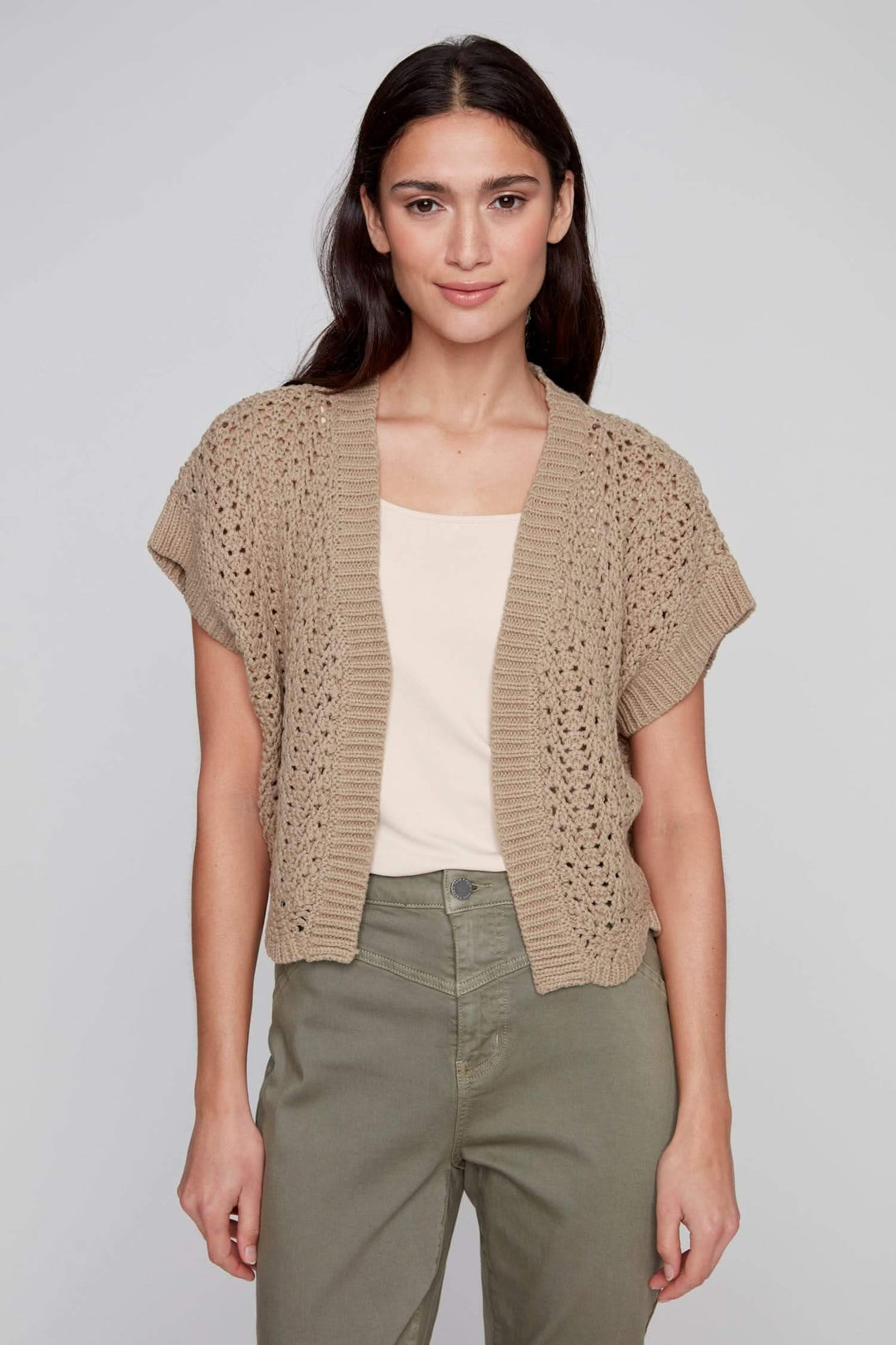 Veste au crochet beige avec manches courtes, portée sur un débardeur pour un look d&