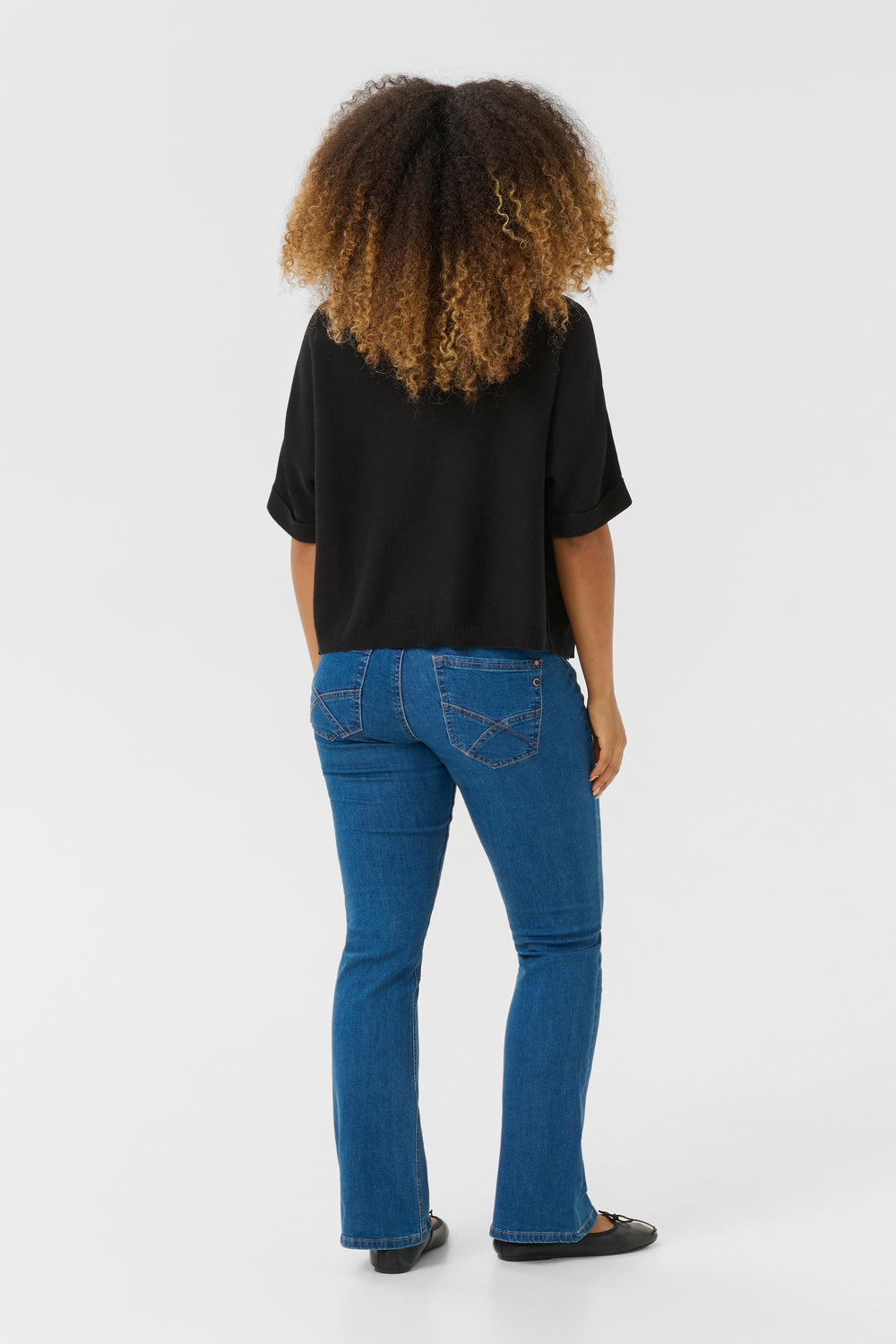 Dos d'une femme portant une Veste avec manches Sillar noire, avec un jean bleu, vue de dos en studio.