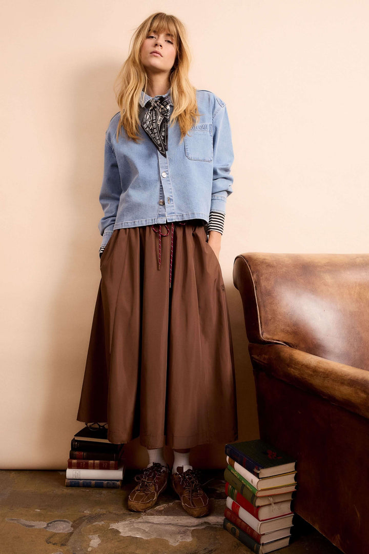 Veste en denim avec coupe décontractée, portée avec une jupe marron pour un look moderne et polyvalent