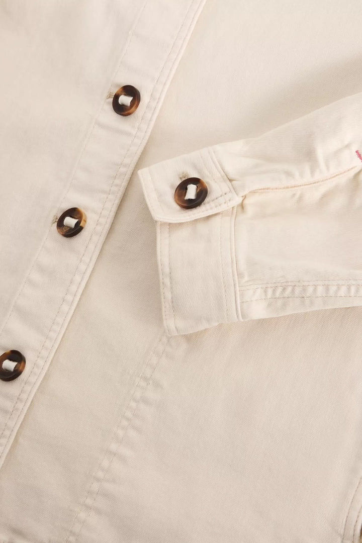 Détail de la Veste en denim Eden à col avec boutons en bois sur tissu crème, style structuré et décontracté.