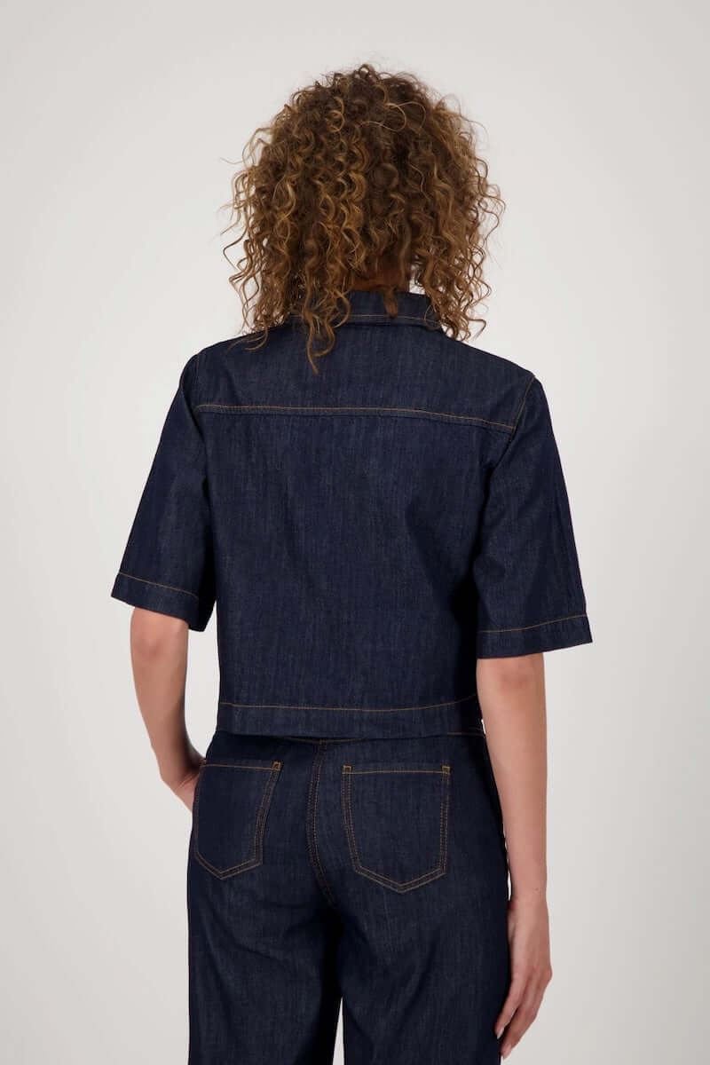 Dos d'une veste en jeans courte avec manches évasées, fermeture boutonnée, sur modèle devant fond blanc, style casual-chic.