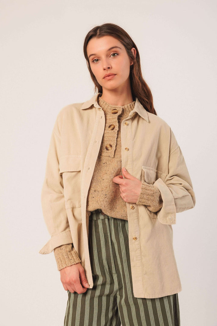 Femme portant une veste en velours côtelé beige avec des poches plaquées, style décontracté.