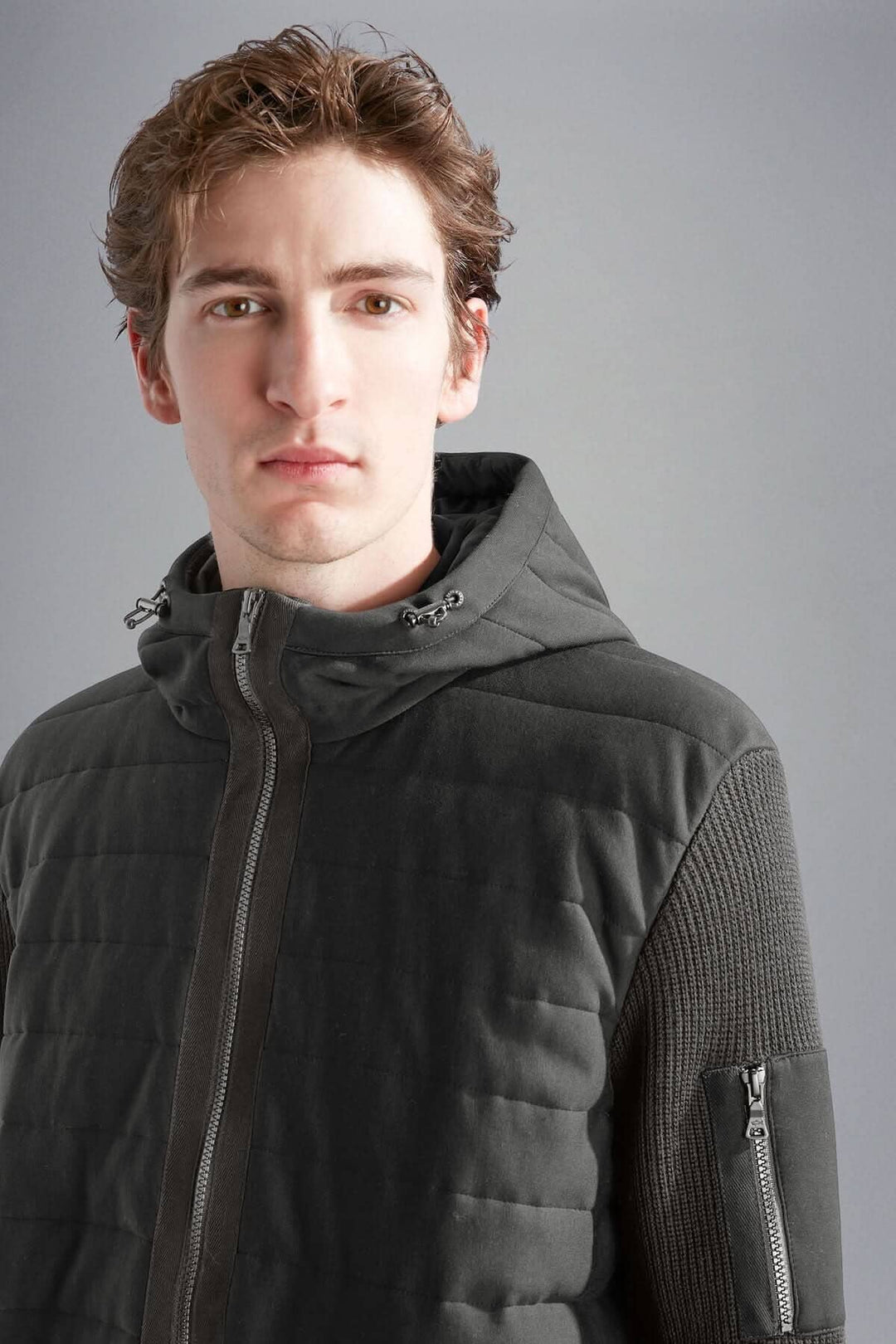 Homme portant une veste imperméable à capuchon Paul &amp; Shark, mélange de matelassage et tricot pour confort et chaleur.