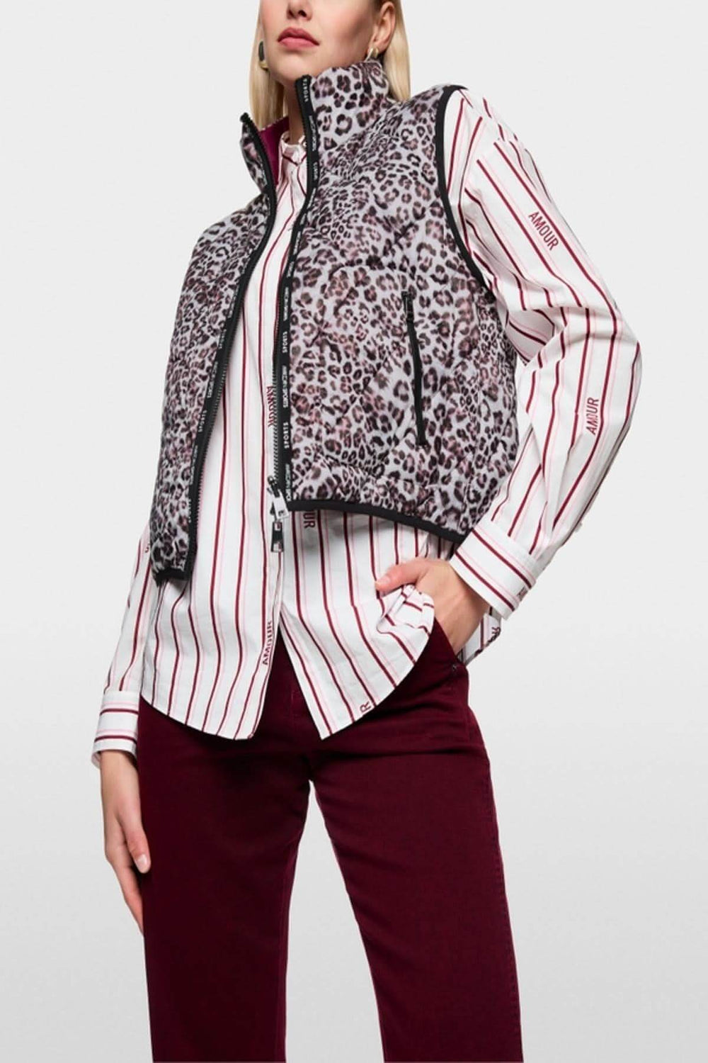Veste sans manche réversible avec imprimé léopard, zippée, col montant et poches latérales, portée par un mannequin sur chemise rayée.