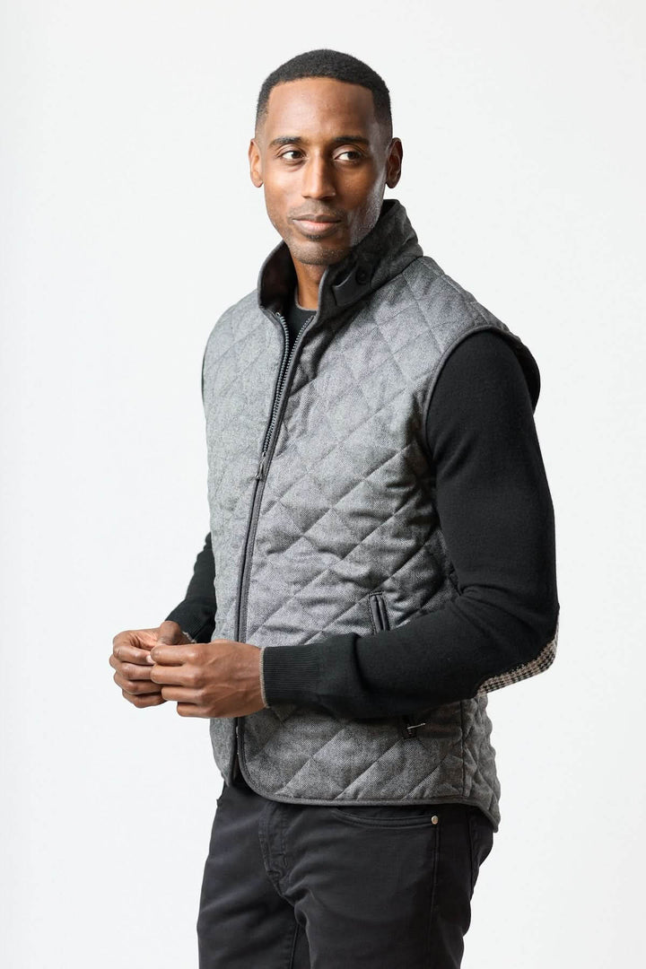 Homme portant une veste sans manches matelassée en laine à motif chevrons, combinant élégance et chaleur pour un style urbain moderne.