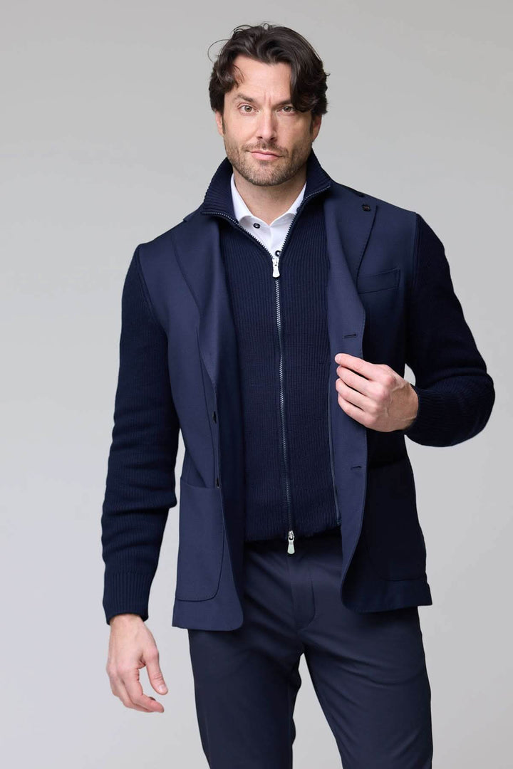Homme portant un veston hybride tricot et tissu bleu avec col à revers et manches en maille, style moderne et sophistiqué.