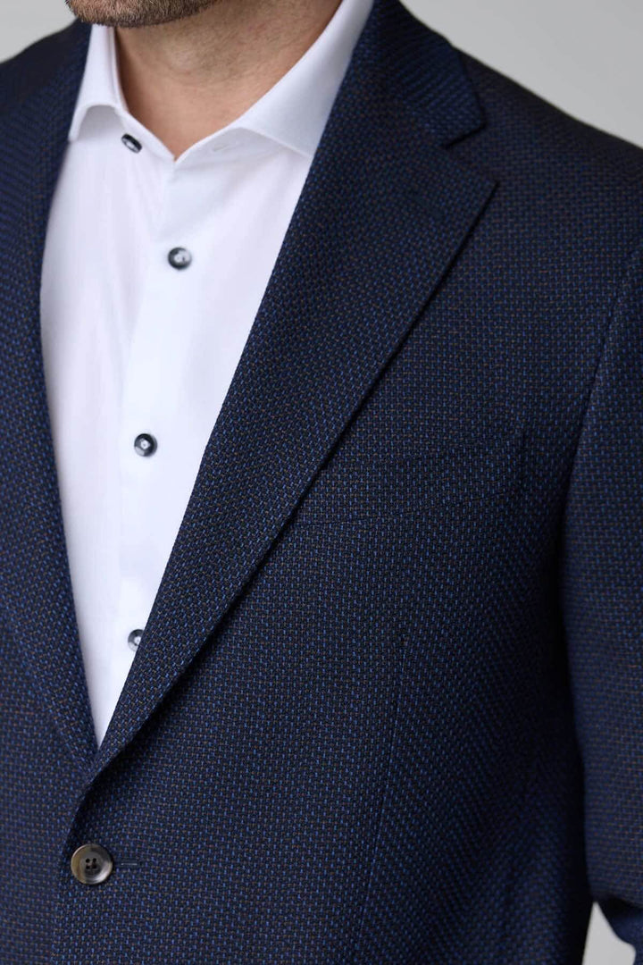Homme portant un veston texturé à coupe moderne avec chemise blanche, parfait pour un style élégant et contemporain.