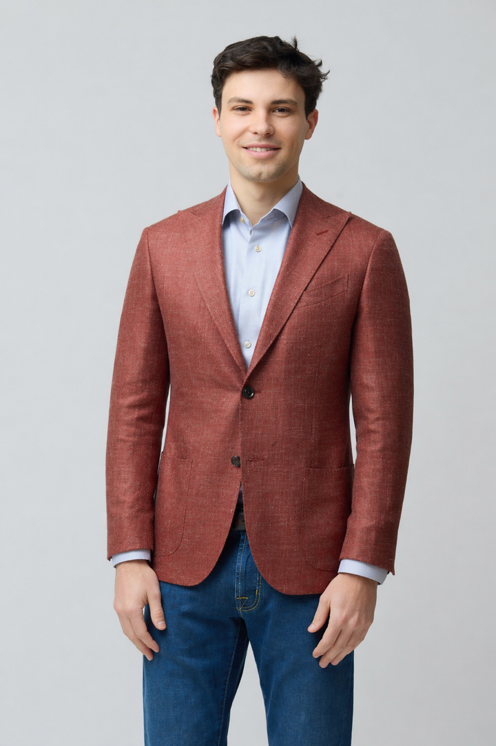 Homme portant un veston texturé en laine, soie et lin, coupe ajustée, couleur rouge, style décontracté chic, avec jeans.