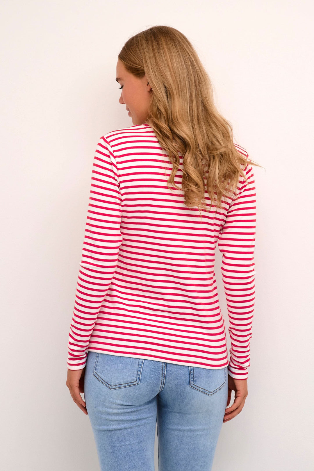 Femme portant un t-shirt à manches longues rayé avec un détail de cœur au dos, associé à un jean.