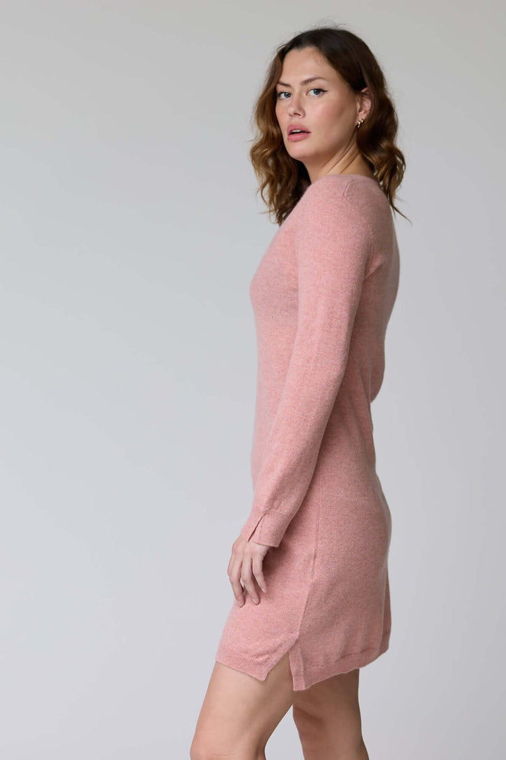 Femme portant la Robe Bonnie en tricot à col en V rose, silhouette féminine, manches longues, coupe droite élégante.