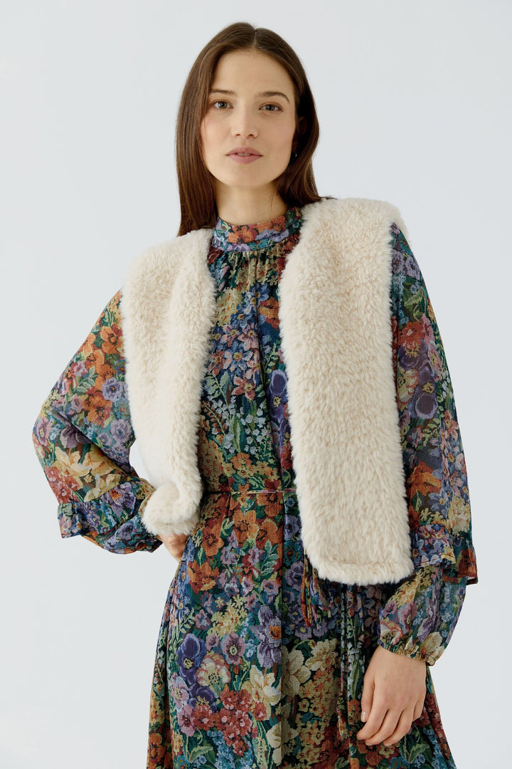 Front view of the beige faux fur-effect sleeveless jacket Oui worn by Valérie Simon