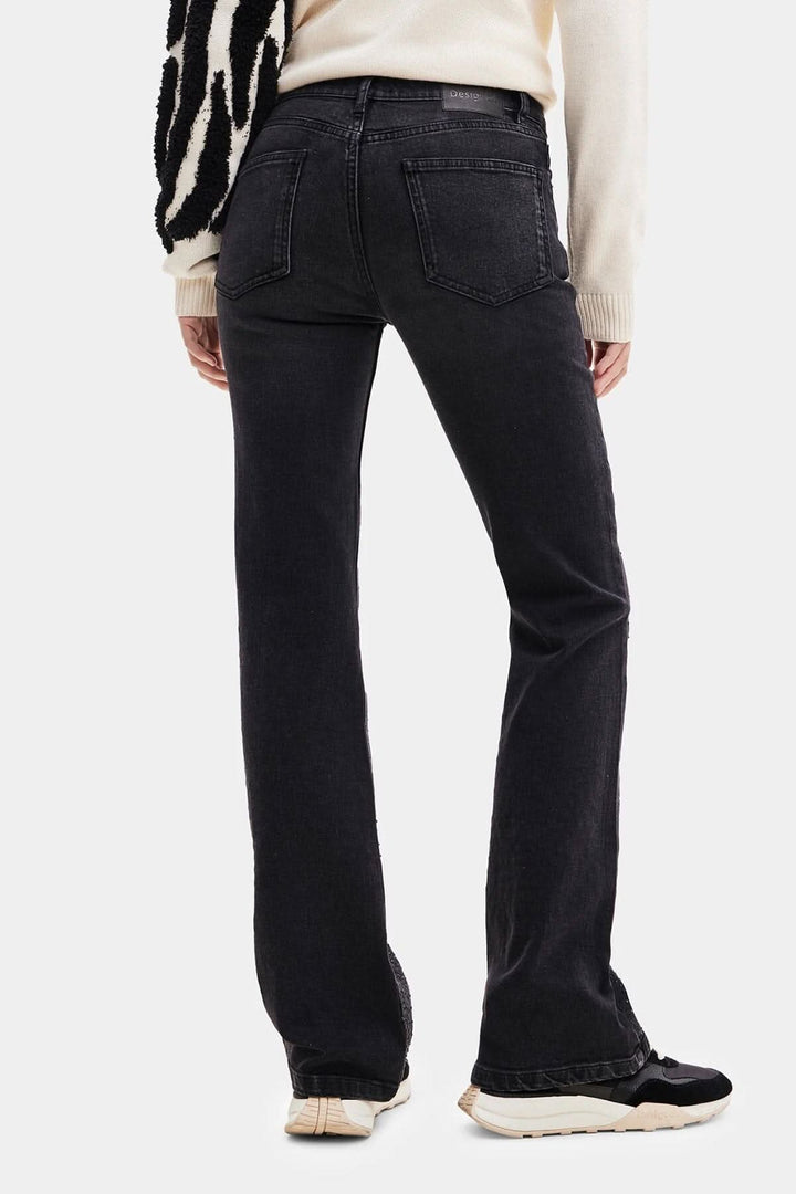 Pantalon noir taille haute avec coupe large et poches, porté de dos par une personne, parfait pour un look décontracté.
