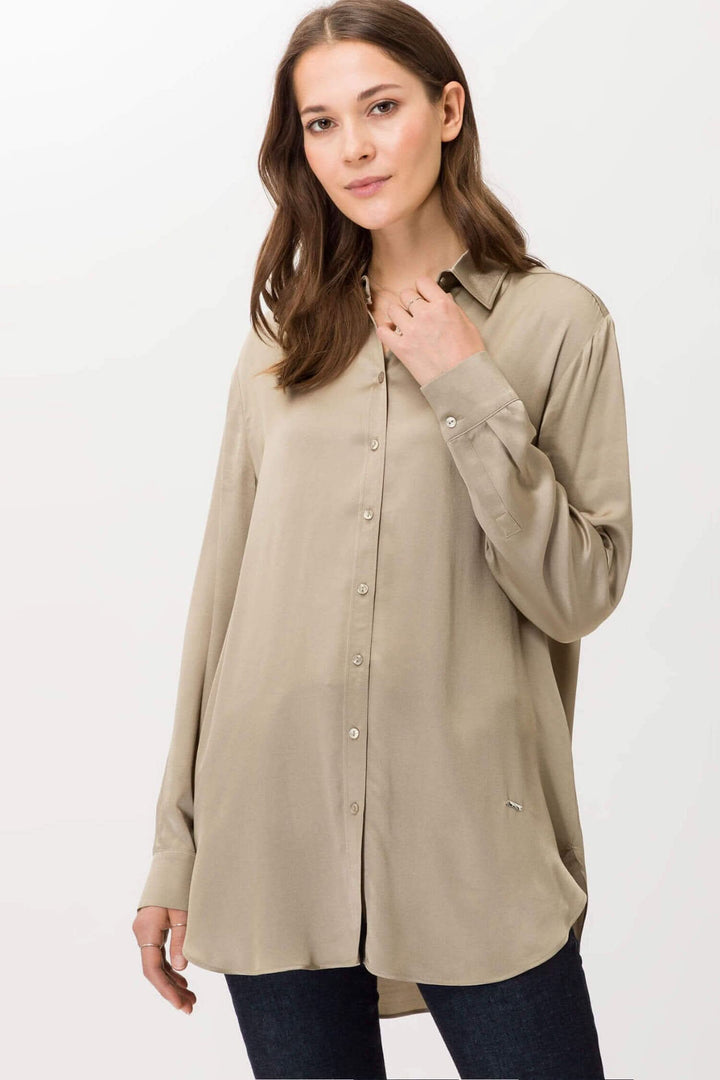 Chemisier en tissu fluide beige à manches longues pour femme, avec col classique et patte de boutonnage.