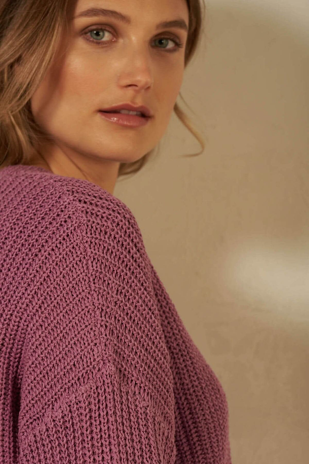 Femme portant un cardigan à mailles violettes, montrant la couture d&