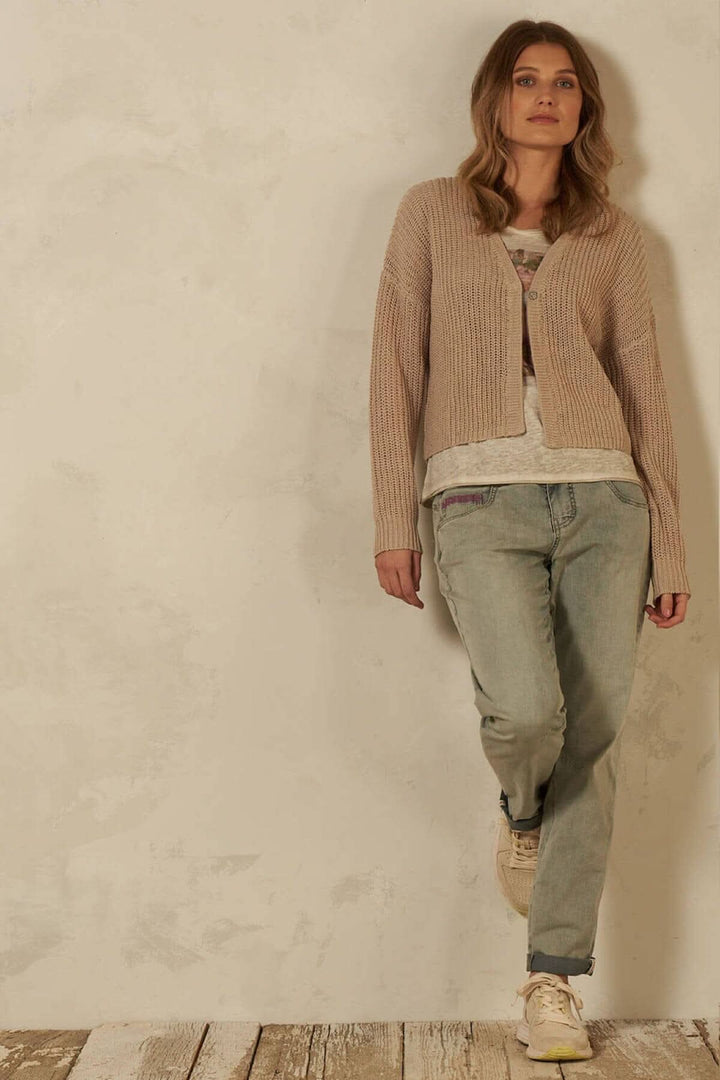 Cardigan à mailles en coton organique, boutons, manches longues, porté par un mannequin avec un style décontracté.