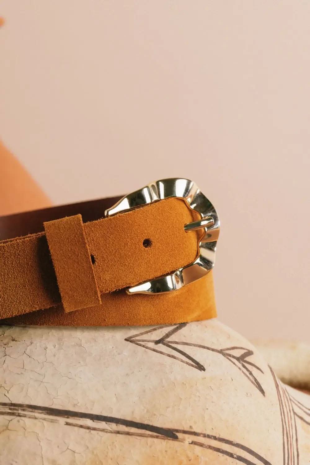 Ceinture en cuir velours coloris cumin avec boucle ondulée en métal doré, style chic et épuré.