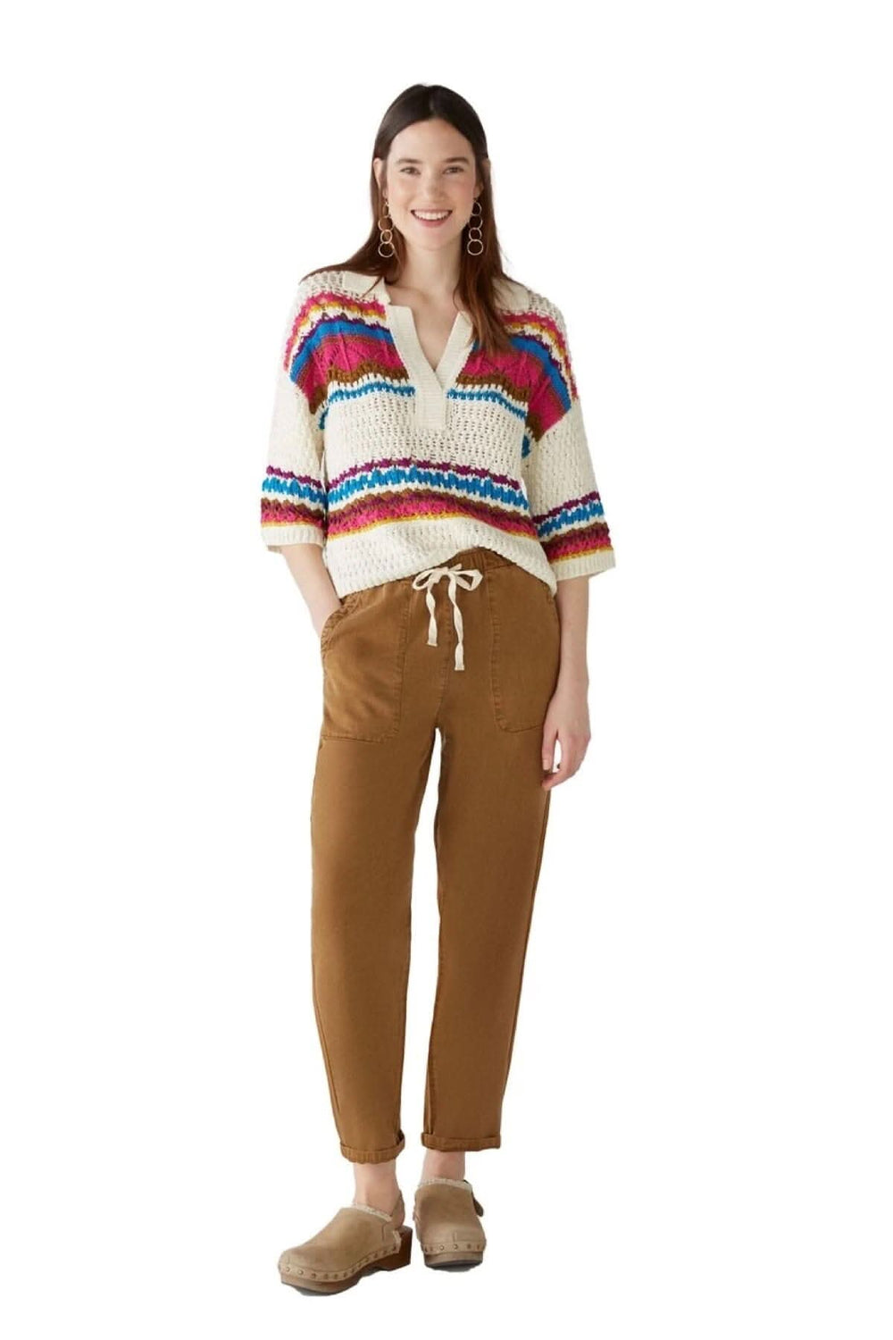Chandail en tricot coloré avec encolure en V, porté avec un pantalon marron et des chaussures confortables.