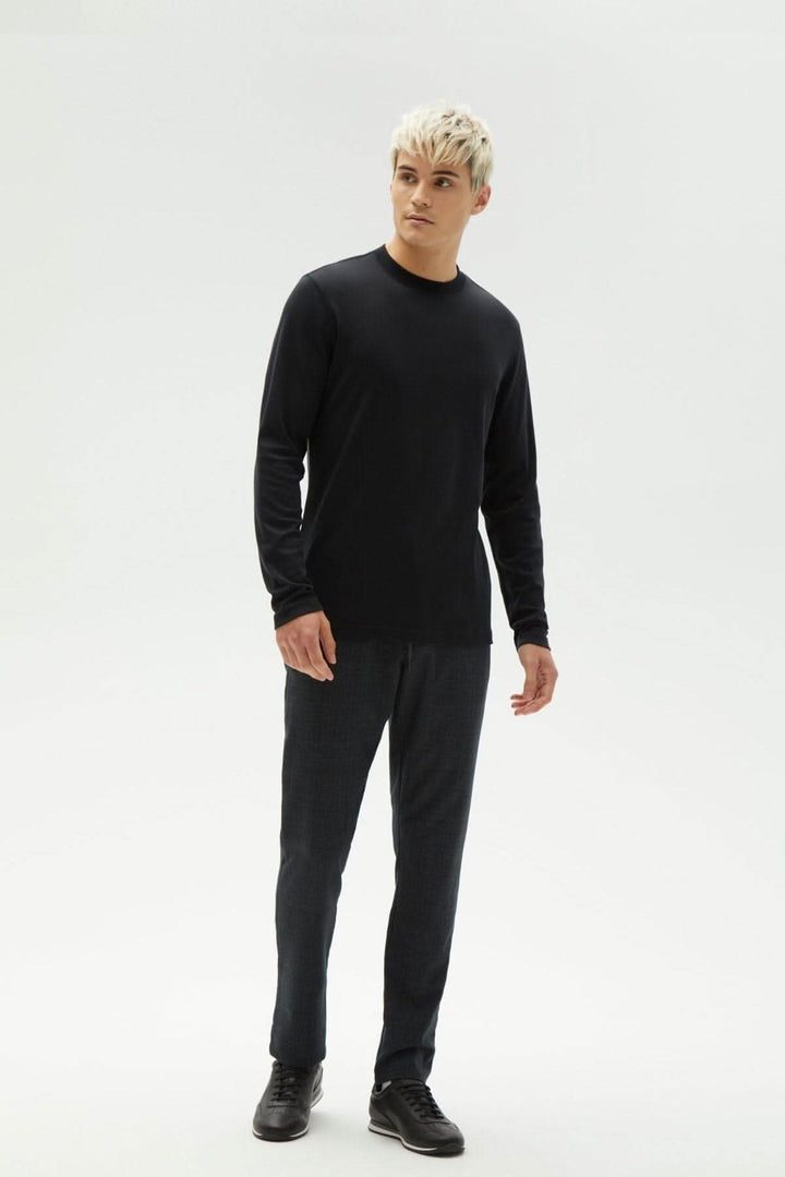 Homme portant un chandail noir à manches longues "Le Barakett" avec un style élégant et confortable.