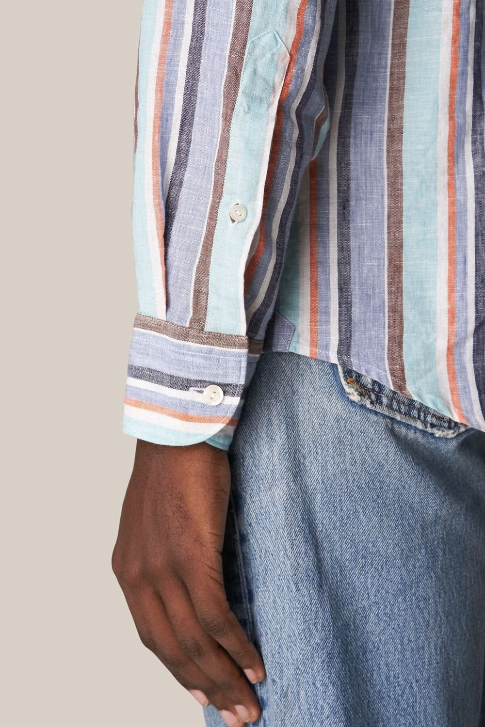 Détail d'une chemise en lin multi-rayures avec un tissage texturé, portée sur un jean.