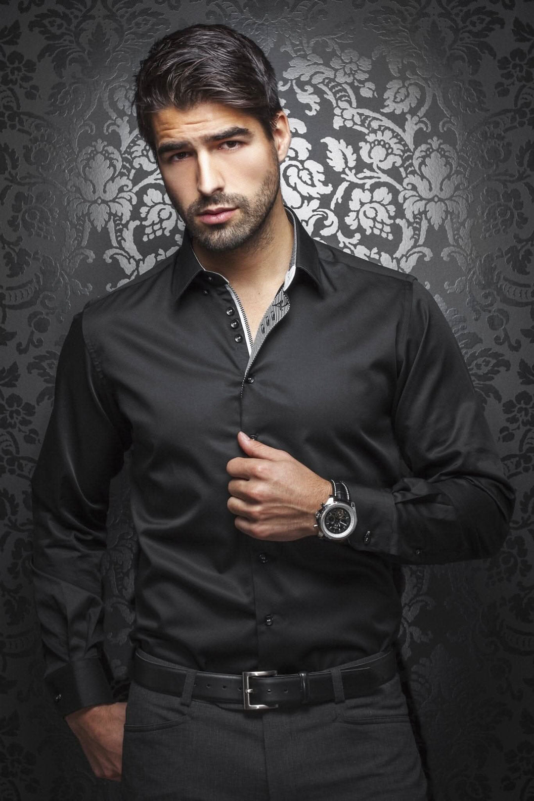 Homme élégant portant une chemise noire habillée avec détails sophistiqués sur fond floral.
