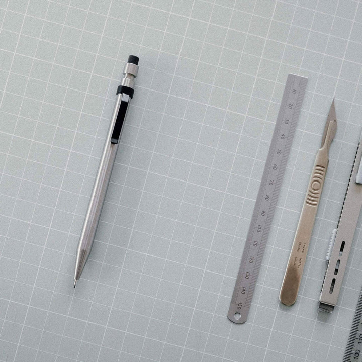 Image de fournitures de bureau incluant un crayon en métal, une règle, un scalpel et d&