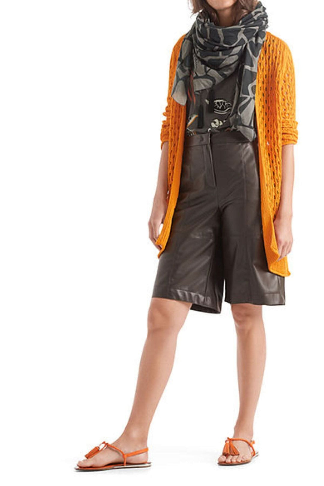 Femme portant un foulard en coton et soie avec motif girafe, cardigan orange, short noir et sandales.