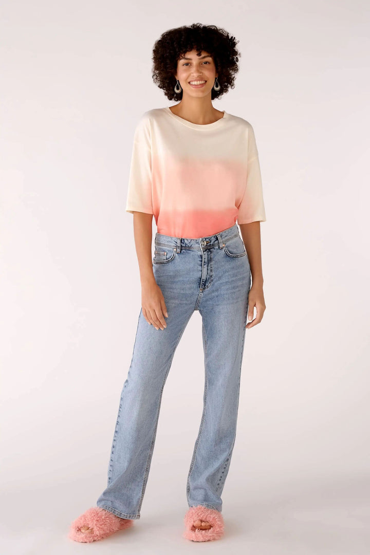 Femme à cheveux bouclés portant un t-shirt dégradé et un jean taille haute, style rétro avec coutures contrastées.