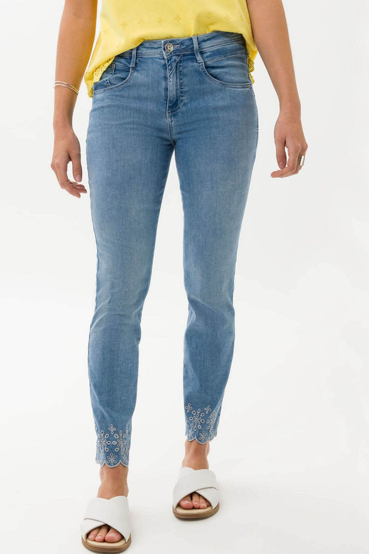 Jean skinny 7/8 féminin avec broderie, porté avec un top jaune et des sandales blanches.