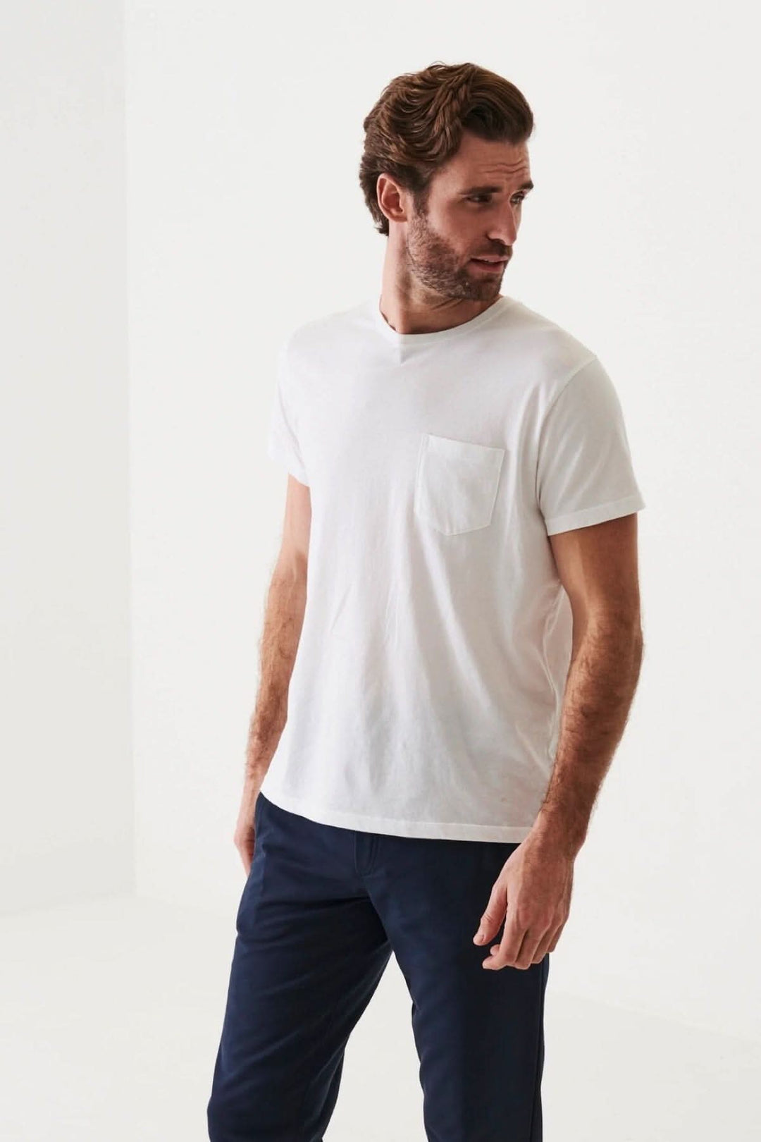 Homme portant un t-shirt léger en coton pima blanc avec une poche, parfait pour les journées chaudes.
