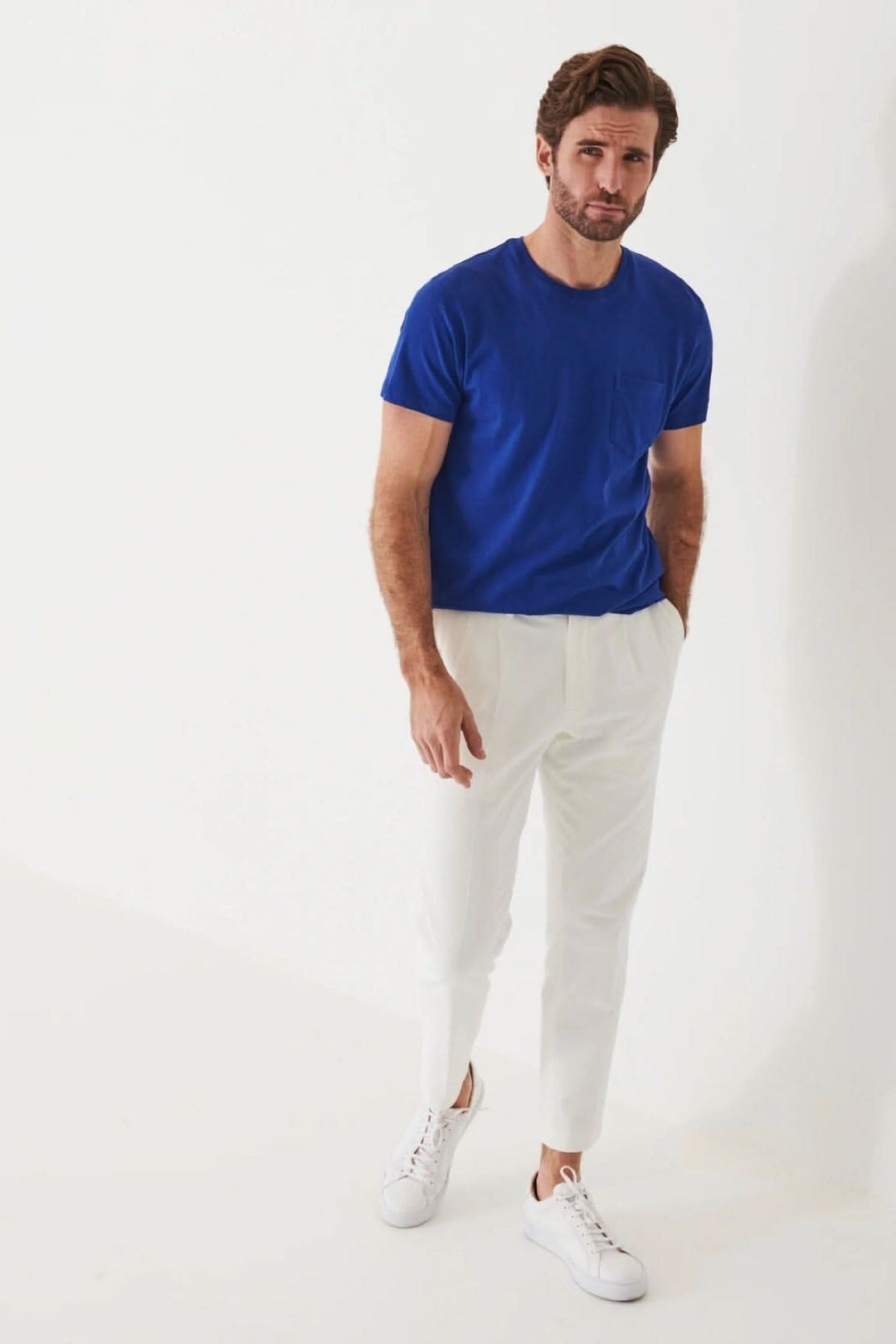 Homme portant un t-shirt léger en coton pima bleu avec une poche, associé à un pantalon blanc.