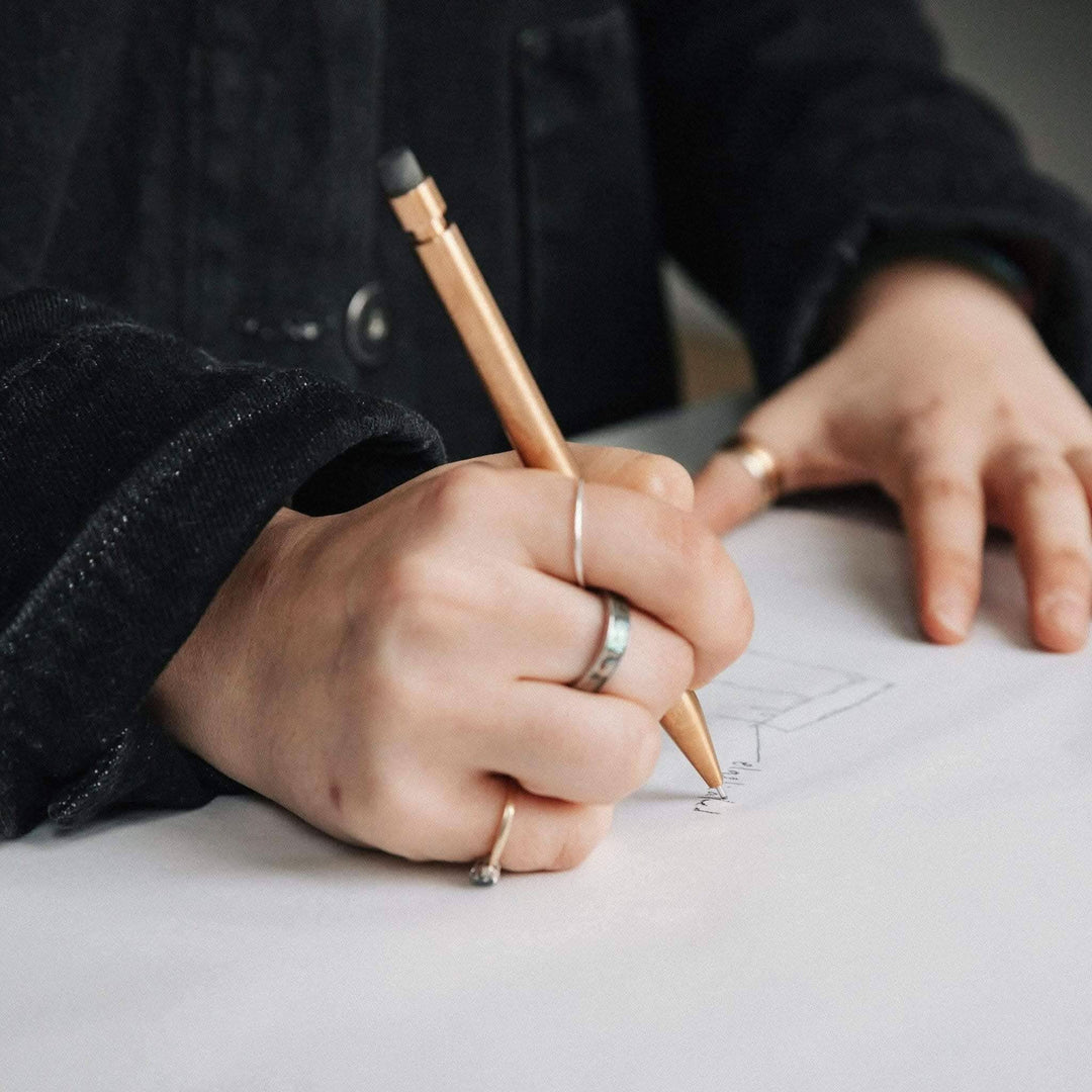Main focus on a hand using a Crayon Modern Fuel to sketch on paper, showcasing its sleek design and engineering.