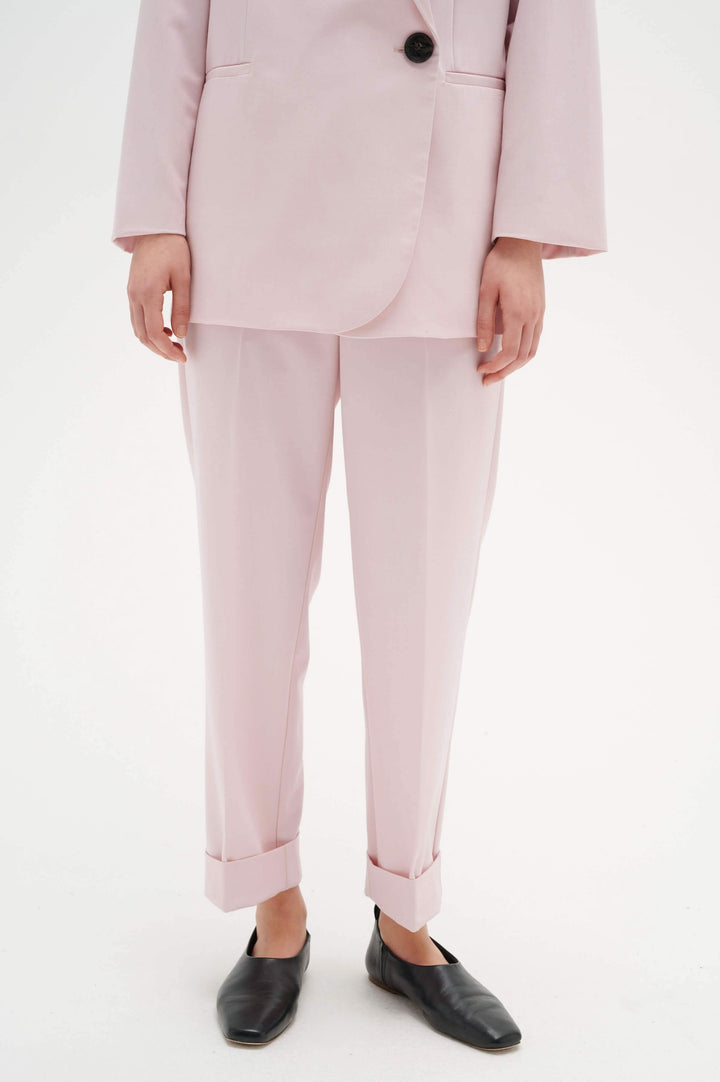 Pantalon à revers Naxa rose avec taille élastique, jambes fuseau et poches, porté avec un veston assorti.